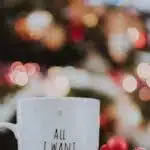 Festive Christmas mug with candy cane, ornaments, and tree lights creating a cozy holiday vibe.